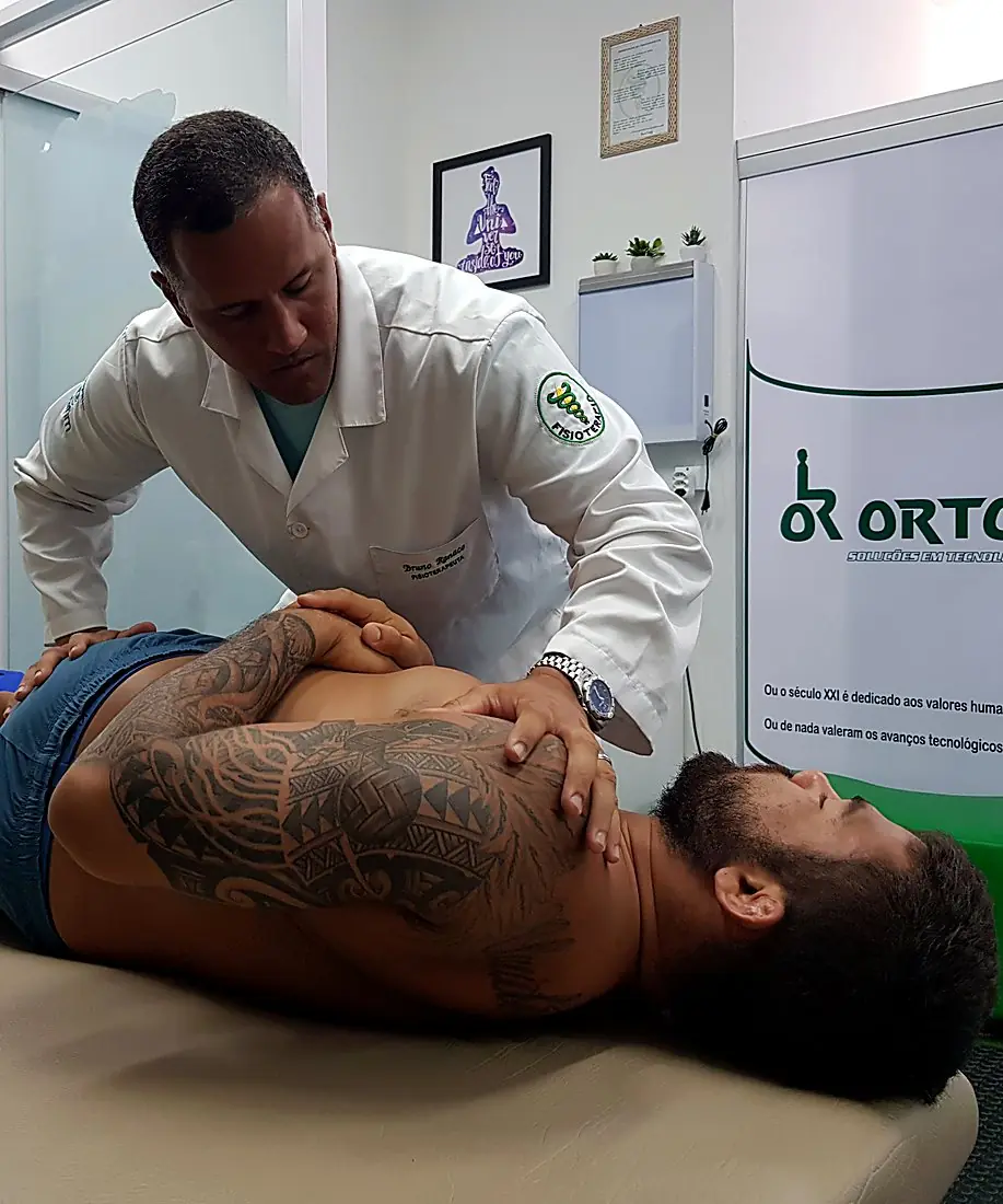 Fisioterapeuta parceiro em atendimento na clínica com o painel da Ortorio ao fundo