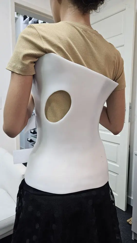 Paciente de costas vestindo o colete 3D branco sobre a camiseta