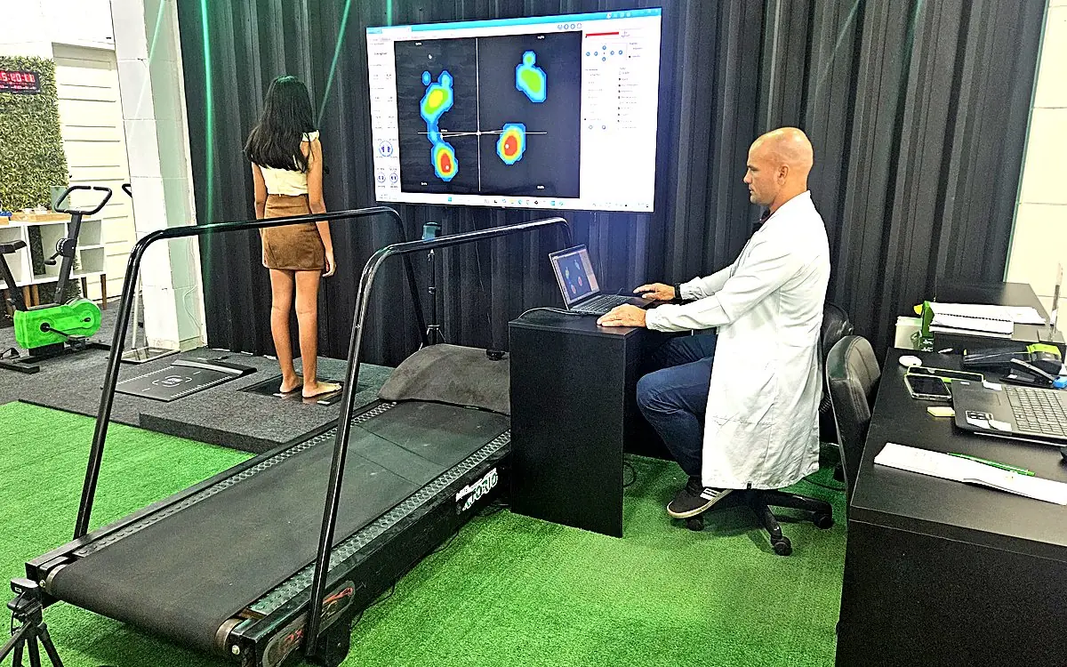 Léo analisando no computador o mapa de pressão plantar da paciente na esteira