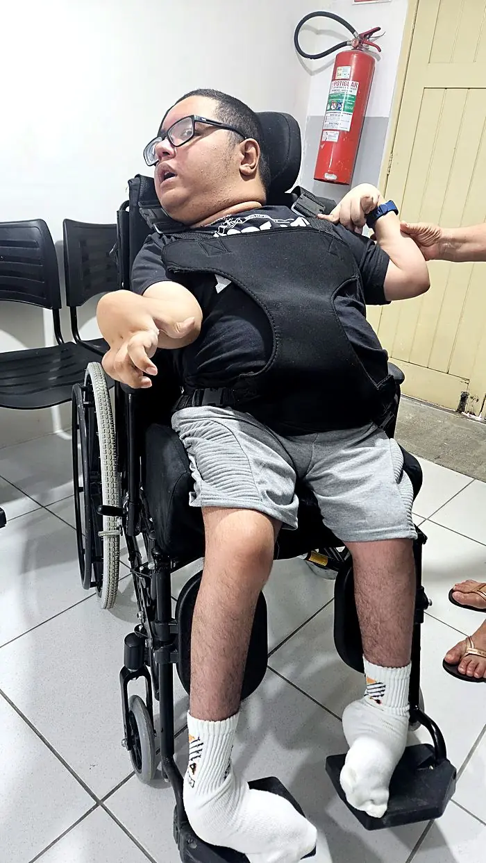 Paciente com órtese de tronco na cadeira de rodas
