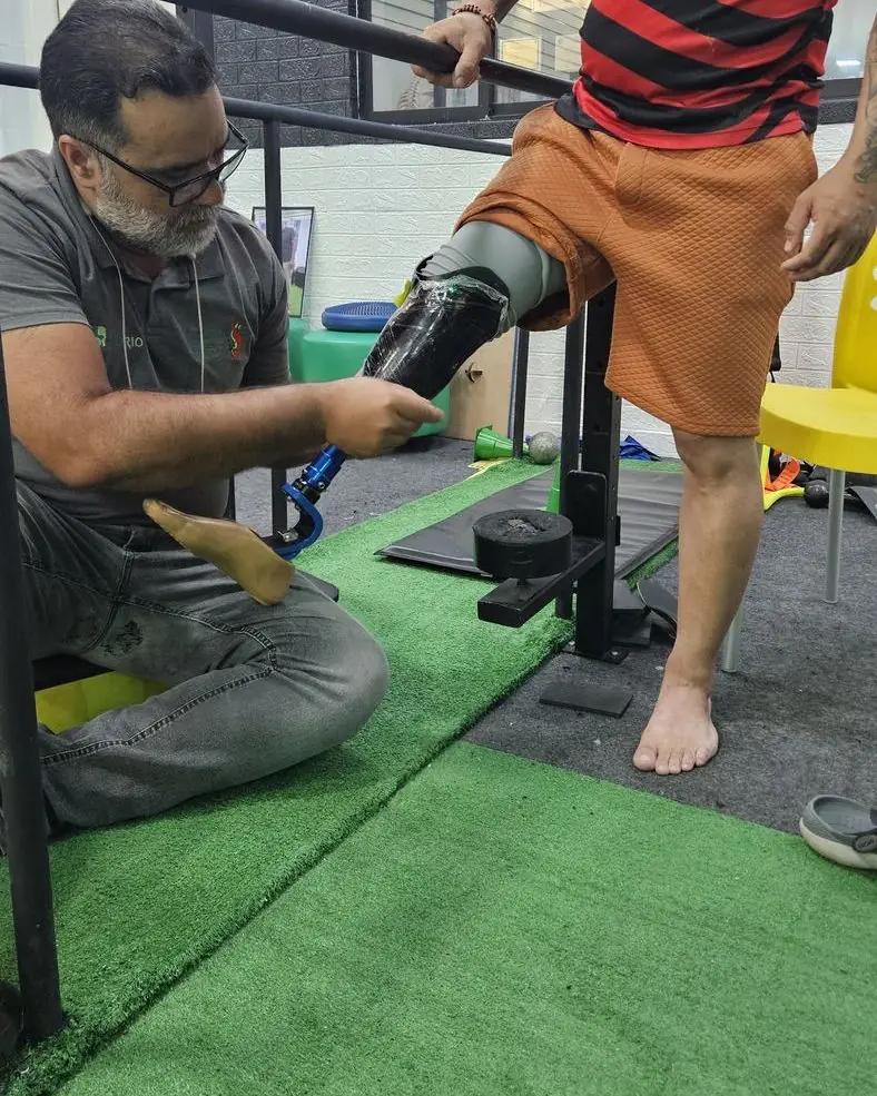 Léo ajustando a prótese de um paciente apoiado na barra paralela