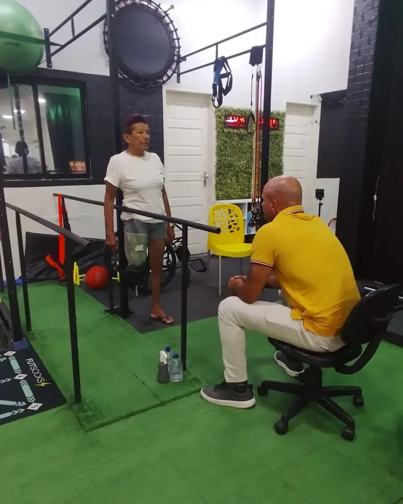 Léo conversando com uma paciente com prótese na barra paralela